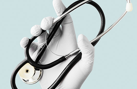 hand-with-latex-glove-holding-a-stethoscope-duting-FMBU4QN